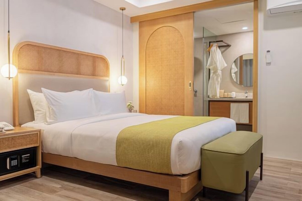 Quarto de hotel com uma cama, mesa de cabeceira e um espelho.