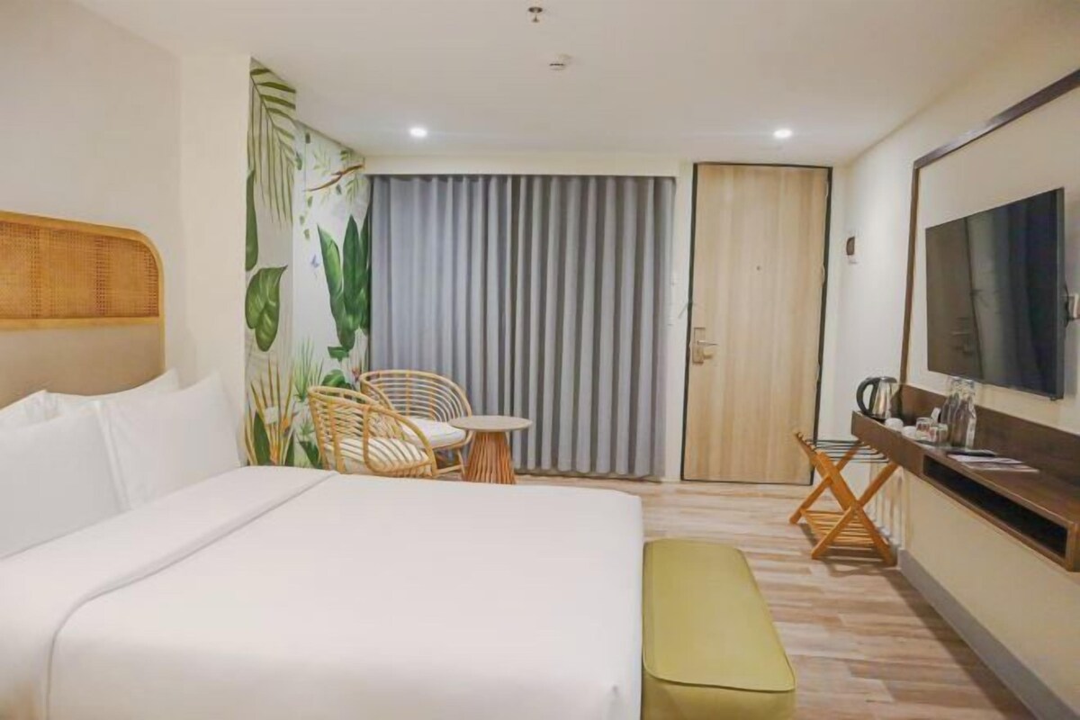 Een hotelkamer met een bed, een bureau, een stoel, een televisie en een schuifdeur.