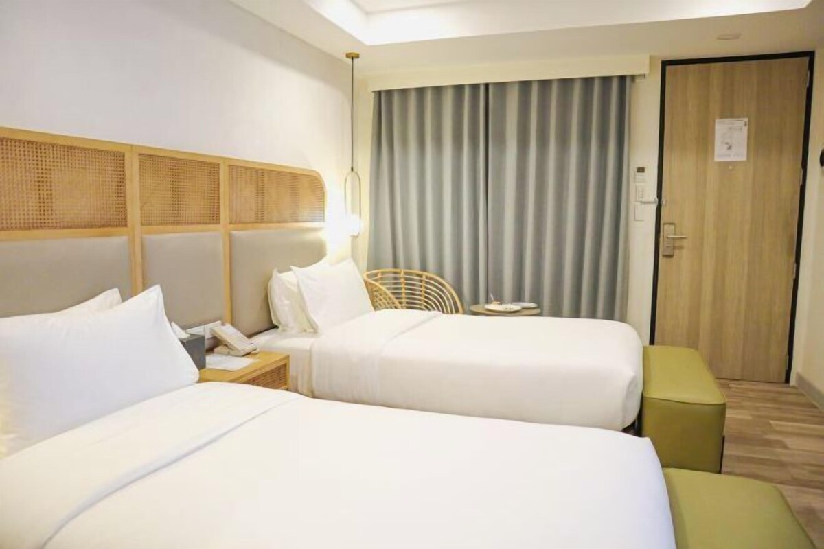 Een hotelkamer met twee bedden, een tafeltje, een stoel en een deur.