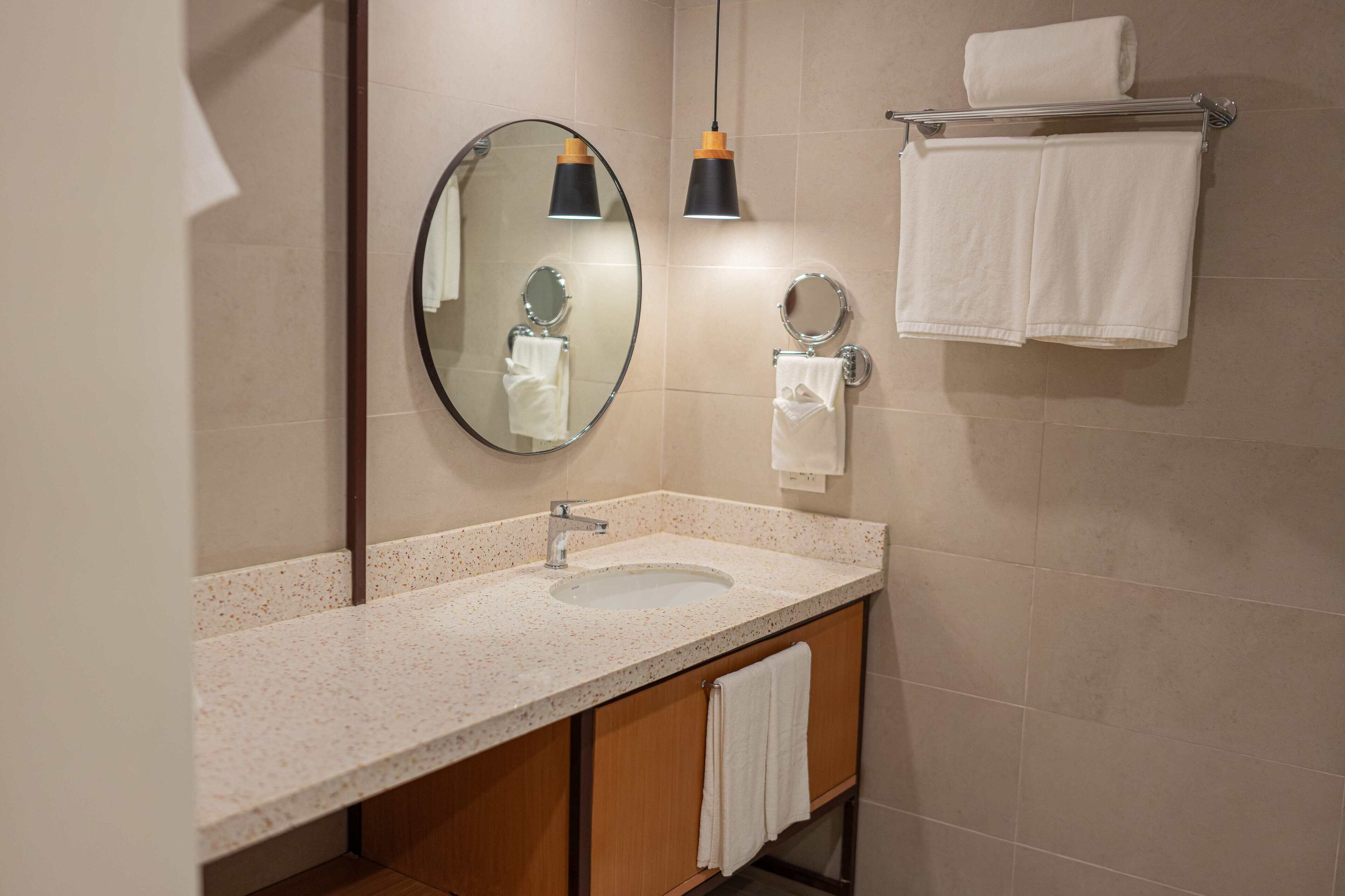 A bathroom with a sink, mirror, towel rack, and two pendant lights.