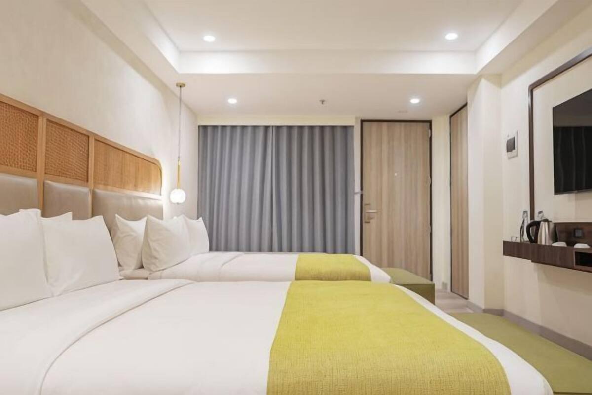 Een hotelkamer met twee bedden, een televisie, een spiegel en een deur naar een badkamer.