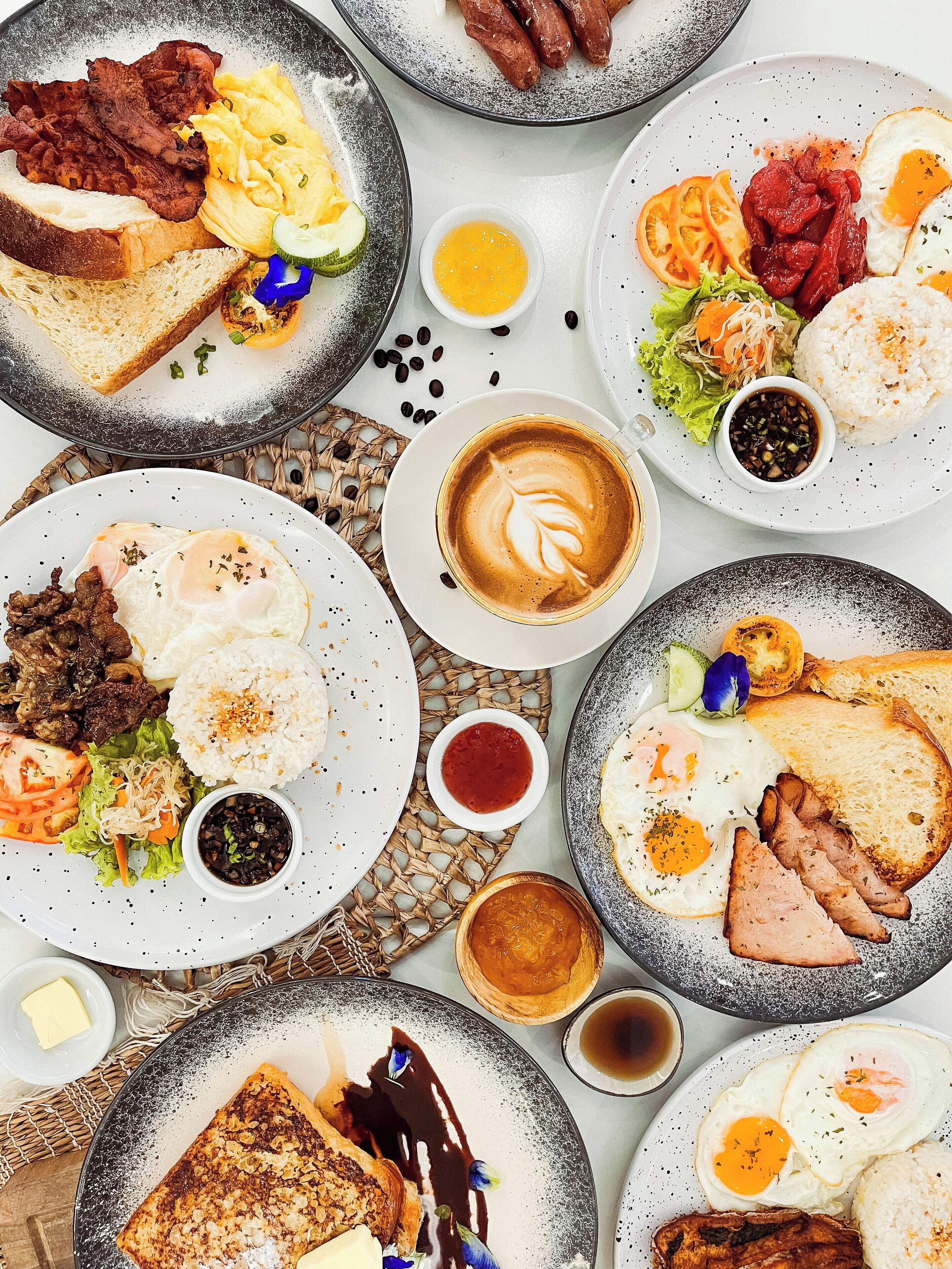 Un assortiment de plats pour le petit-déjeuner, notamment des œufs, des saucisses, des toasts et du café.