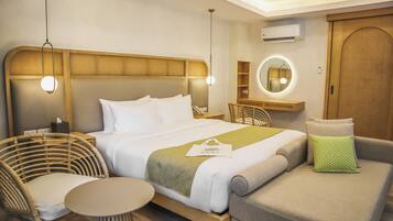 A modern hotel room with a bed, a round mirror, a small table, and a seating area.