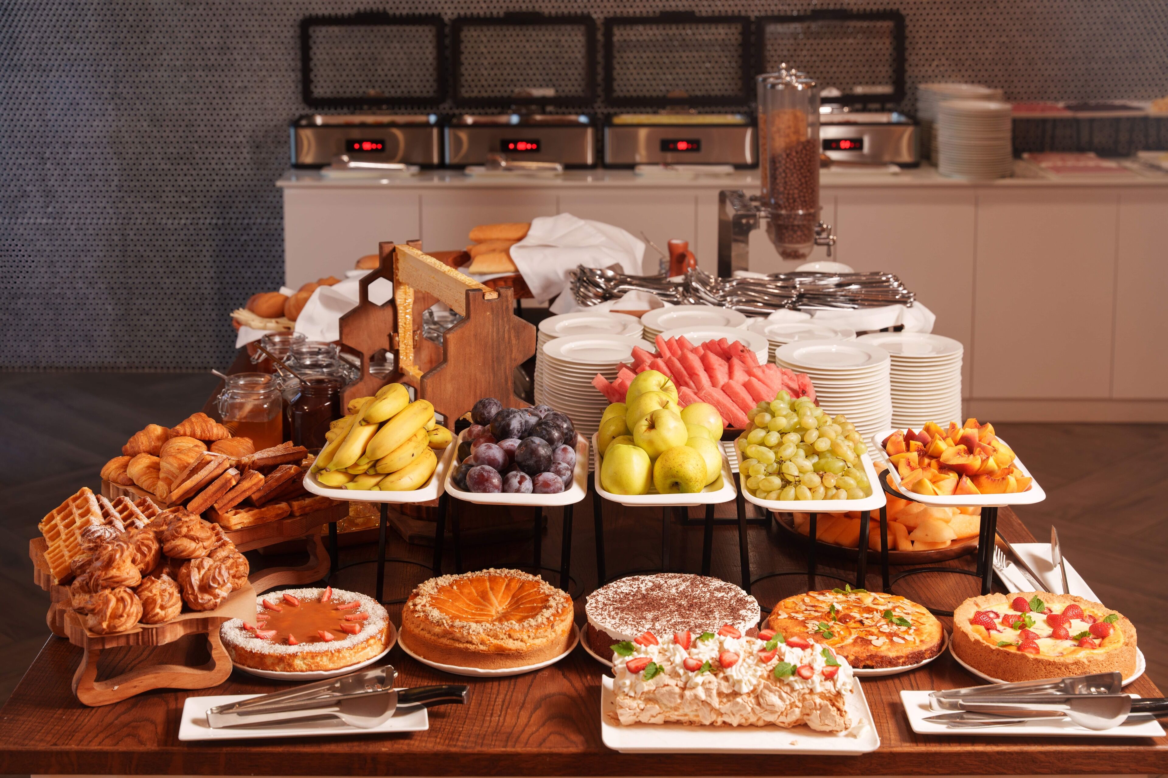 Taula de buffet amb diferents aliments, com ara pastissos, fruita i pastissos.