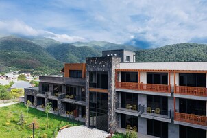 Un edificio de varios pisos con balcones, fachada de piedra y vistas a montañas.