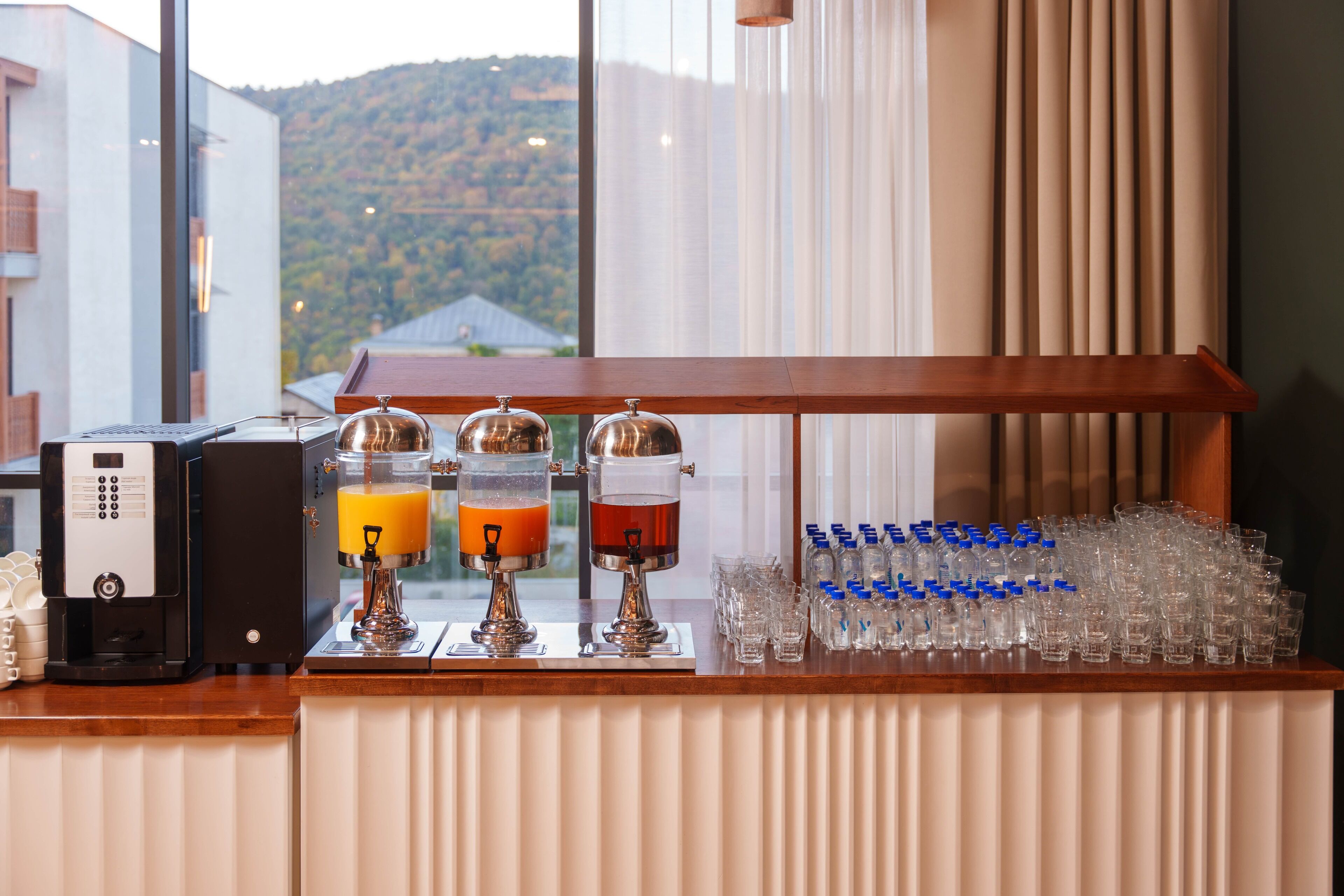 A bar area with a coffee machine, two beverage dispensers, and a row of glasses.