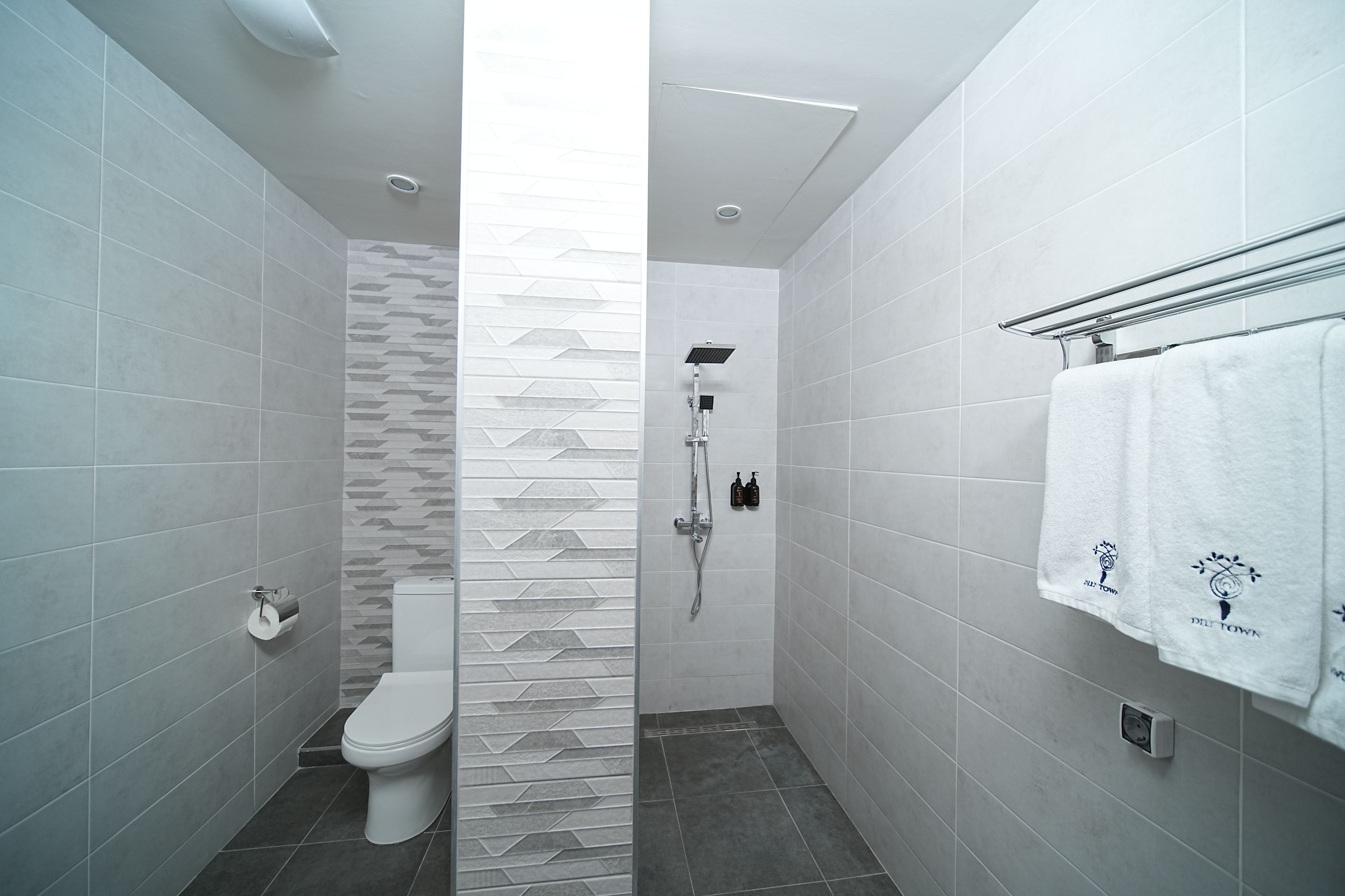 Une salle de bain moderne équipée de toilettes, d’une douche et d’un porte-serviettes.