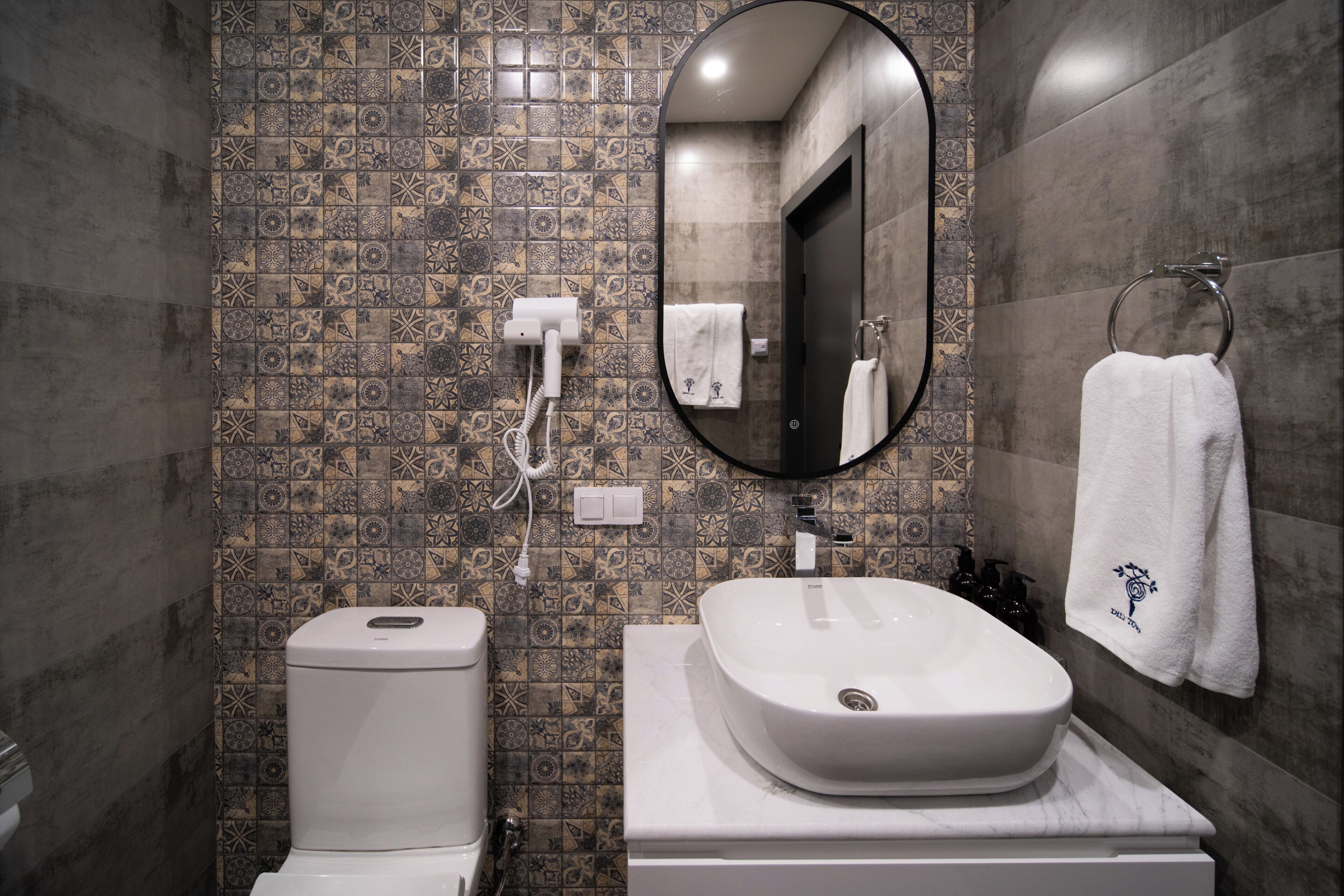 A bathroom with a toilet, bidet, sink, and a mirror.