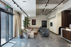 A modern lobby with a reception desk, seating area, and a large window. - Dili Town Resort and Spa (Dilijan)