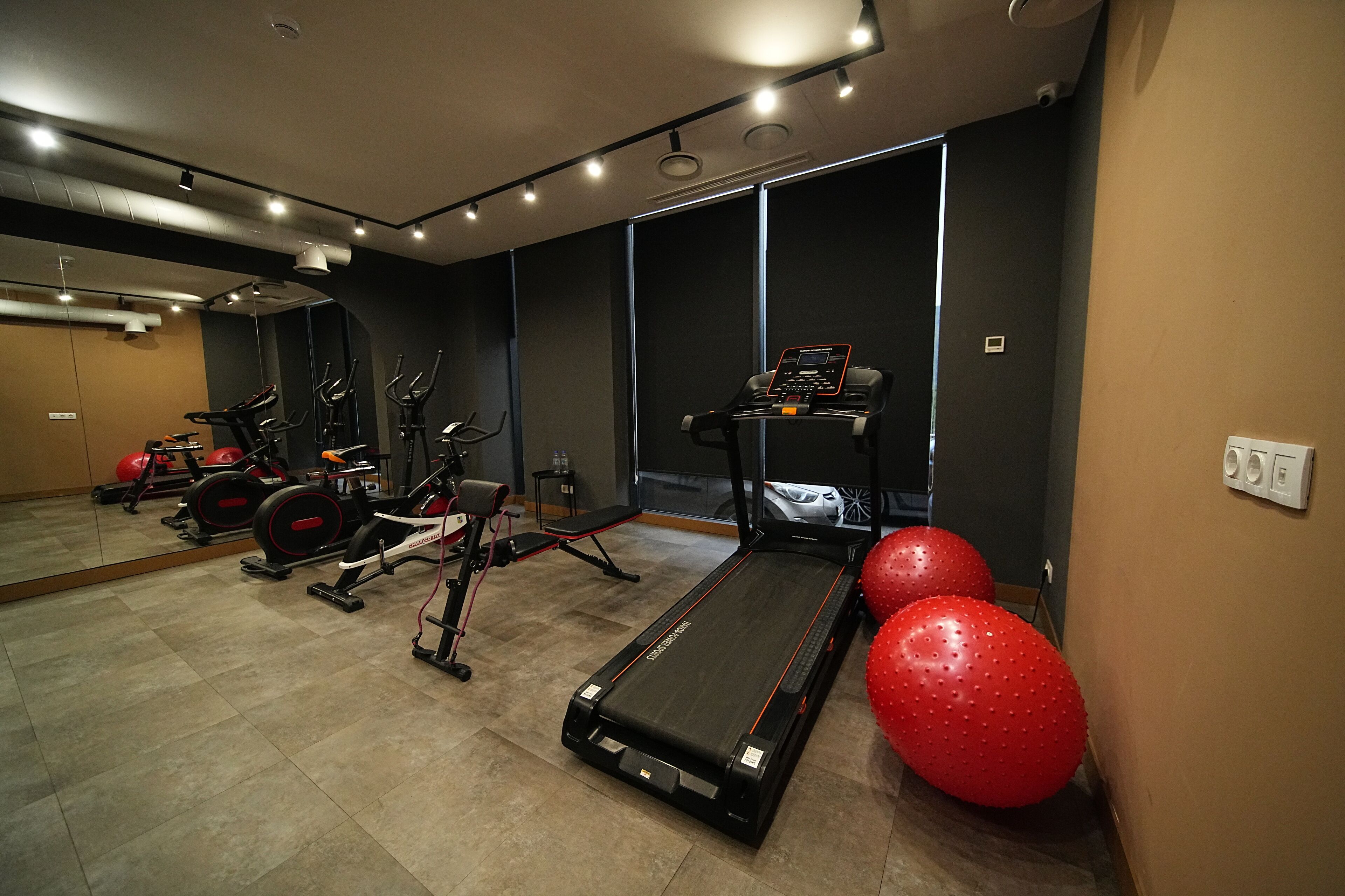 A gym with treadmills, elliptical machines, and red exercise balls.