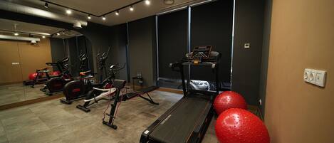 A gym with treadmills, elliptical machines, and red exercise balls.