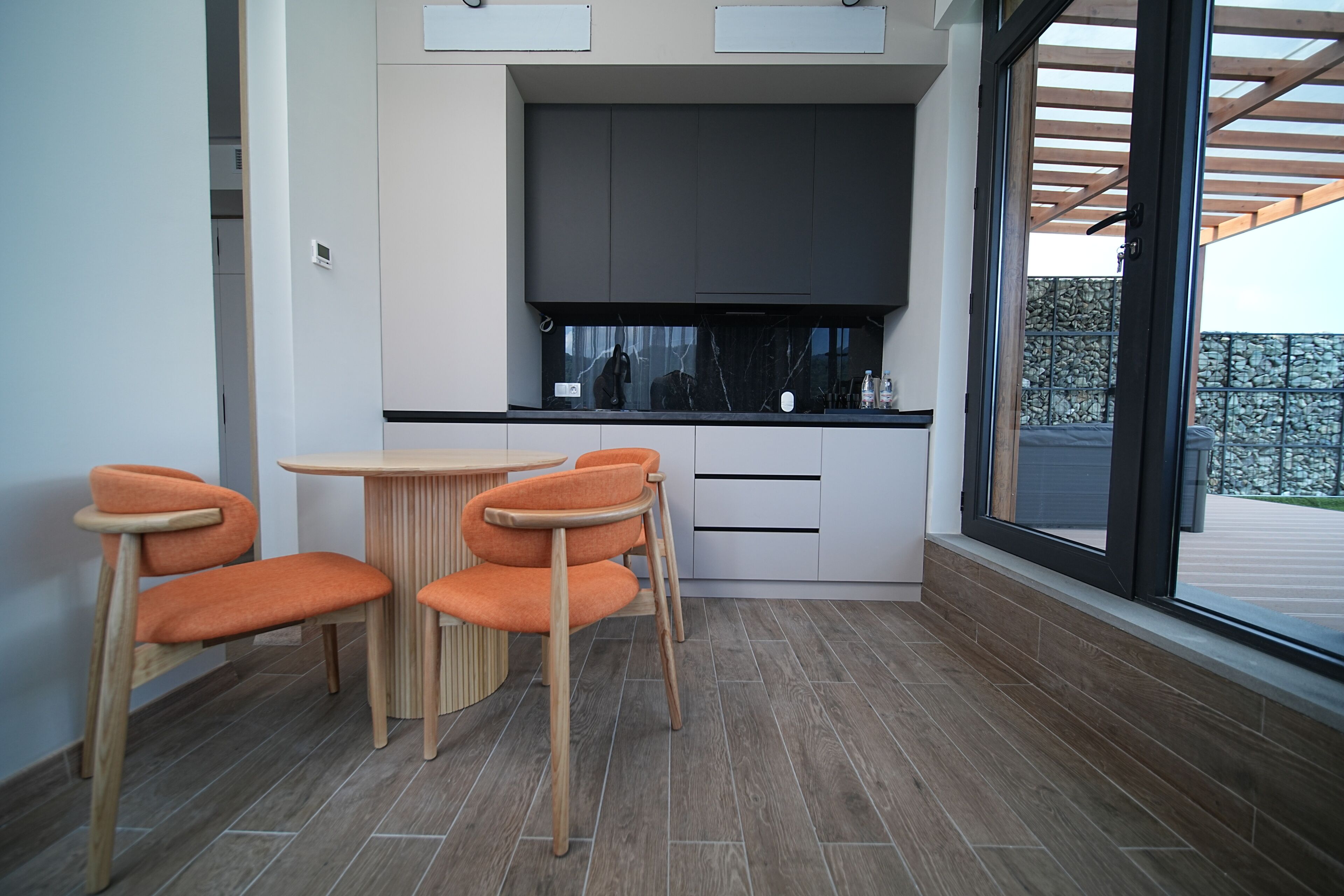Eine moderne Küche mit großem Fenster, einem Esstisch mit Stühlen und Blick ins Freie.