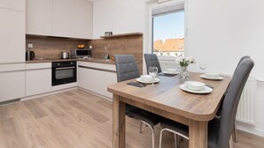 A modern kitchen with white cabinets, a wooden countertop, and a dining area with a wooden table and chairs.