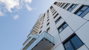 Ein modernes Hochhaus mit mehreren Balkonen und großen Fenstern.