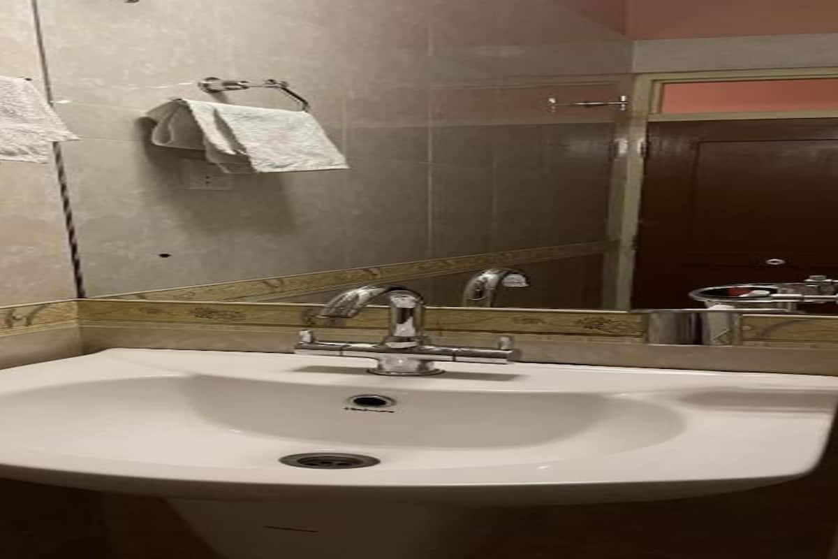 A bathroom with a white sink, two towel racks, and a mirror.