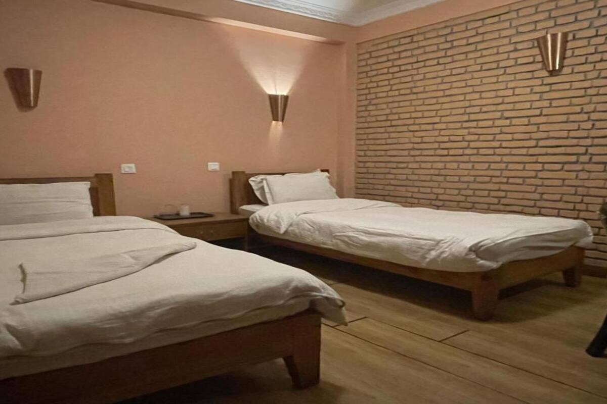 A room with two beds, a brick wall, and a chair.