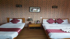 Una camera d'albergo con due letti singoli, un comodino in legno, una lampada, un quadro appeso alla parete e una parete con motivo a mattoni.