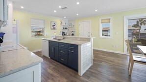 Une cuisine moderne dotée d’un îlot central, de meubles blancs et offrant une vue sur l’extérieur.