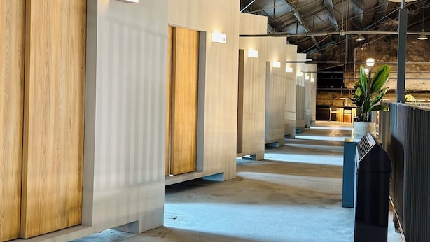 A modern interior with rows of rooms, each with a wooden panel and a number sign. - KW2 Hostel   (Kaohsiung)