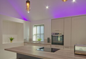 A modern kitchen with a central island, built-in oven, and pendant lighting.