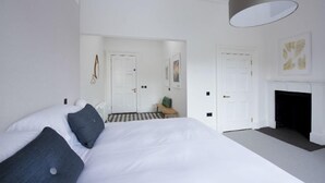 A modern bedroom with a large bed, a checkered floor, a fireplace, and a hallway leading to another room. - Harris (Isle of Lewis)