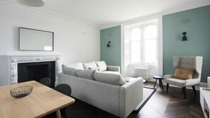 A modern living room with a fireplace, a sofa, a dining table, and a chair. - Airinis (Isle of Lewis)