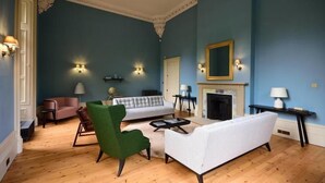 A living room with a blue wall, a fireplace, and a green armchair. - Airinis (Isle of Lewis)