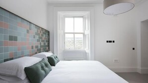 A bedroom with a large bed, a tiled headboard, a window, and a radiator. - Airinis (Isle of Lewis)