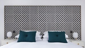 A bed with white bedding, two teal pillows, and a patterned headboard. - Seaforth (Isle of Lewis)