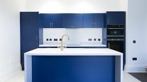 Una cucina moderna con isola centrale, mobili bianchi e dettagli blu scuro.