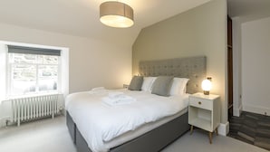 A modern bedroom with a large bed, a bedside table with a lamp, and a window with a view of the outdoors. - Seaforth South (Isle of Lewis)