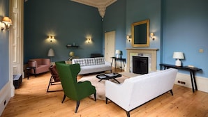 A living room with a blue wall, a fireplace, and a green armchair. - Seaforth South (Isle of Lewis)