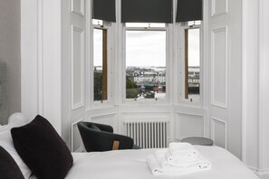 Habitación de hotel con un gran ventanal que ofrece vistas panorámicas de la ciudad.