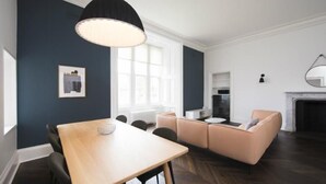 Un salon moderne avec une table à manger en bois, un canapé beige et une suspension noire.