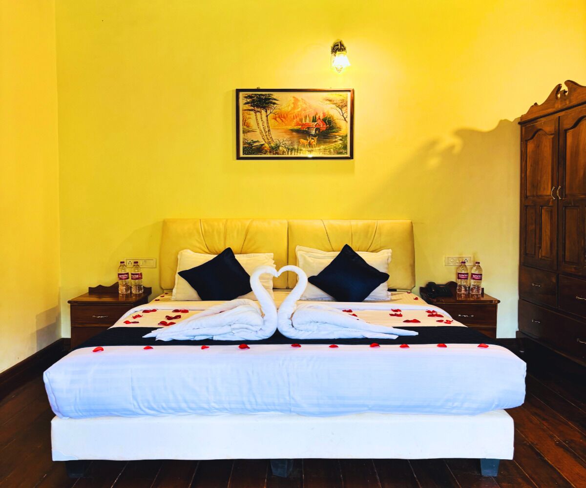 A hotel room with a large bed, two nightstands, a wooden wardrobe, and a painting on the wall.