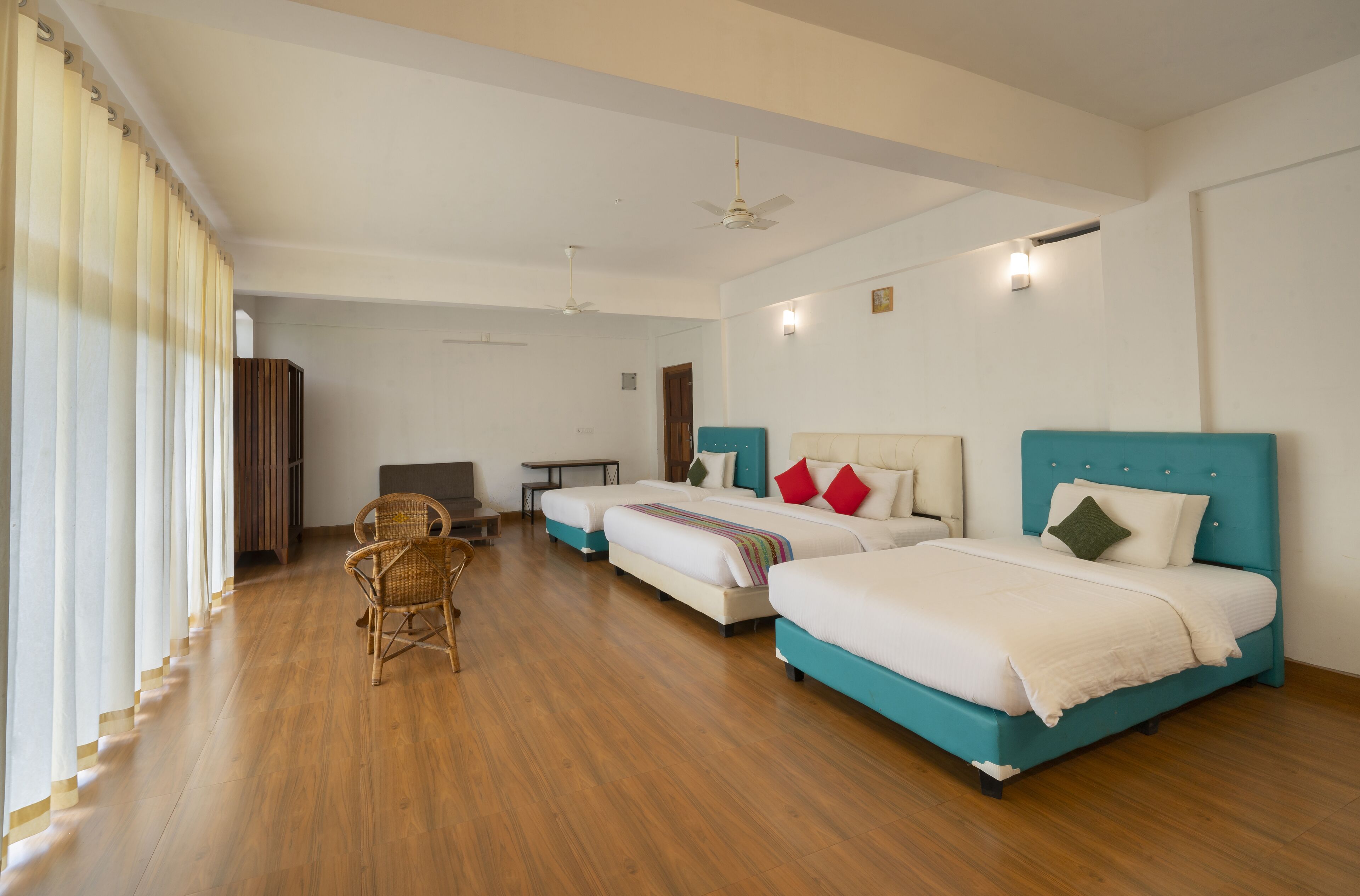 Habitación de hotel con dos camas, piso de madera, una silla y un escritorio.