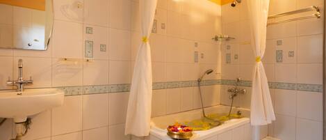A bathroom with a bathtub, a sink, and a shower area.