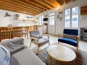 Una sala de estar acogedora con muebles de madera, un televisor y una cocina con salpicadero de ladrillo.