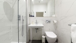 A modern bathroom with a glass-enclosed shower, a white sink, and a toilet. - Ranol East (Isle of Lewis)