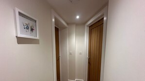 A hallway with wooden flooring, white walls, and a wooden door. - Fowey - Crimpers Cottage (Fowey)