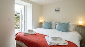 A bedroom with a bed, two bedside lamps, a window, and a wall-mounted picture. - Fowey - Crimpers Cottage (Fowey)