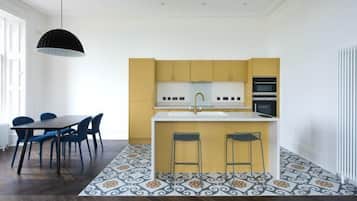 A modern kitchen with a central island, yellow cabinets, and a black pendant light.