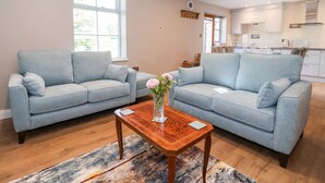 Un salon moderne avec deux canapés bleu clair, une table basse en bois et un tapis aux couleurs vives.