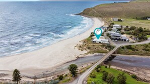 A coastal property with a beach view, a road leading to the houses, and a dolphin icon indicating a nearby attraction. - Myponga Dunes - 1 Hewett Crescent, Myponga Beach (Myponga Beach)