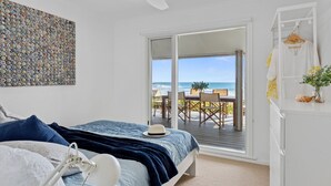 A bedroom with a bed, a view of the ocean, and a balcony with outdoor furniture. - Myponga Dunes - 1 Hewett Crescent, Myponga Beach (Myponga Beach)