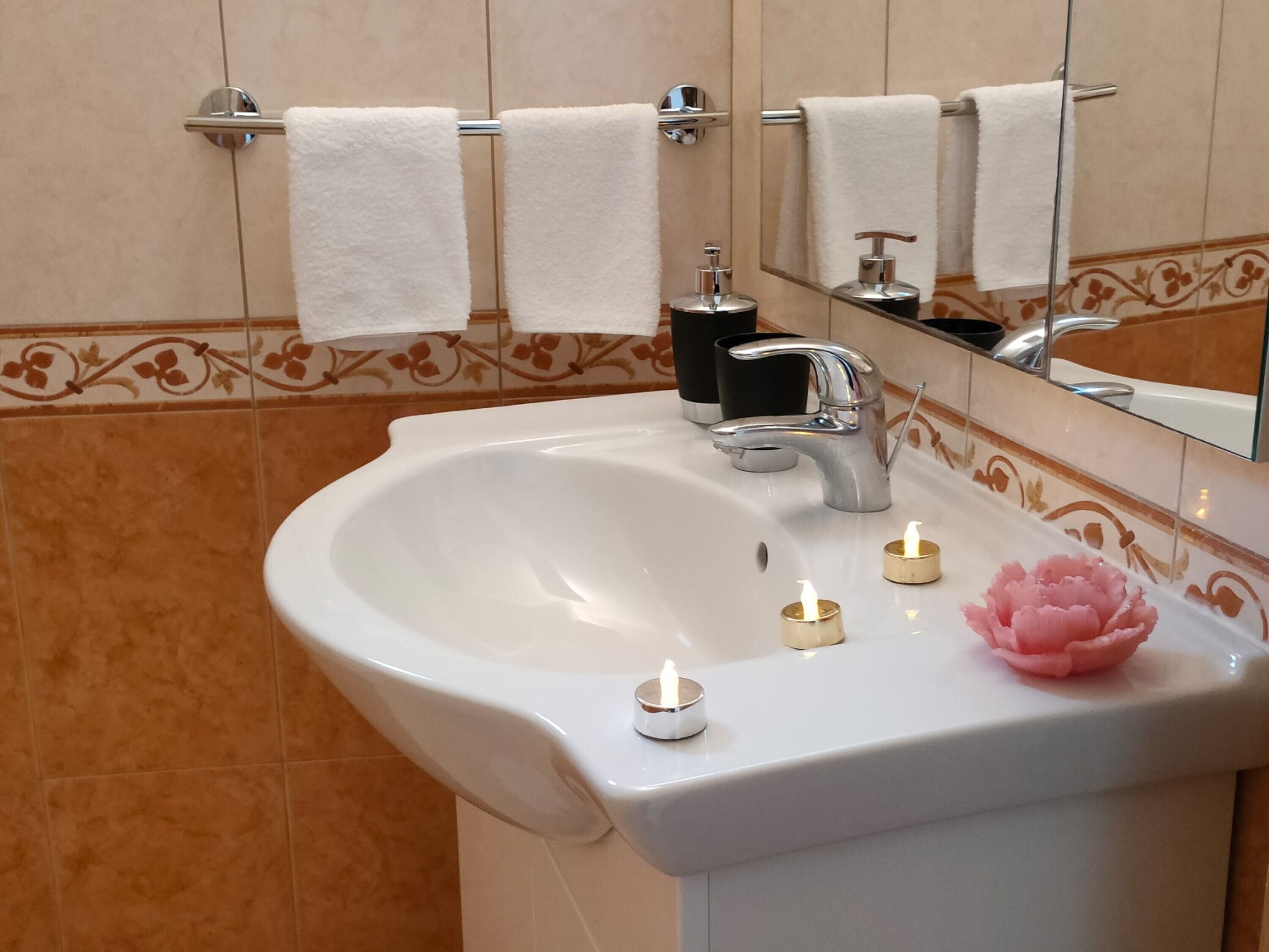 A bathroom with a white sink, a mirror, and a towel rack with two white towels.