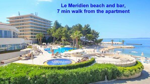 A resort pool area with a circular water feature, lounge chairs, and umbrellas. - A5 Beachfront apt With a Balcony and sea View (Podstrana)