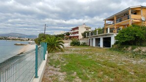 A coastal property with a fenced yard, a beach, and a view of the sea.