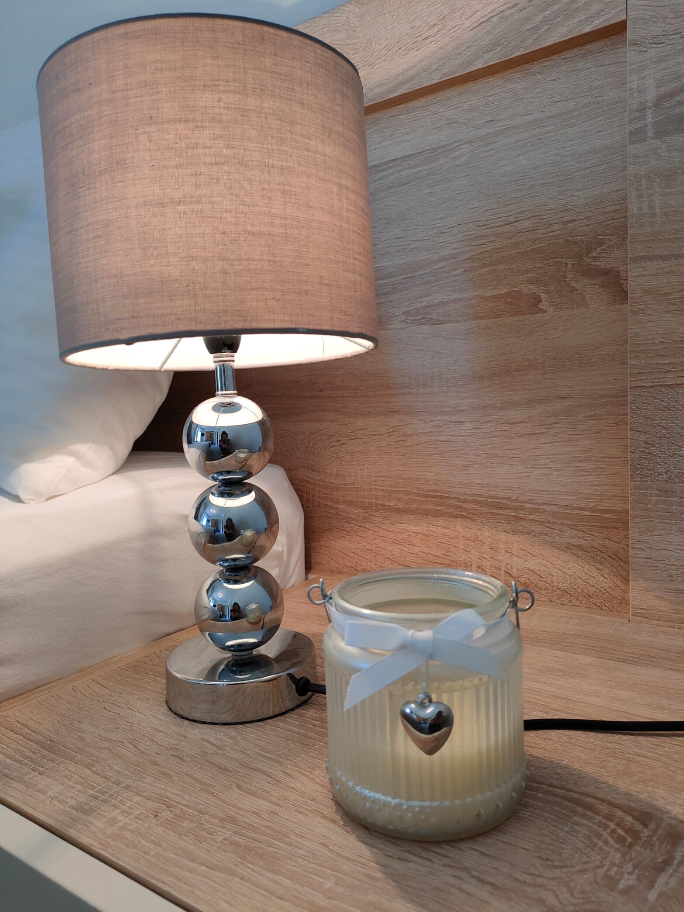 A bedside table with a lamp and a jar of candles.