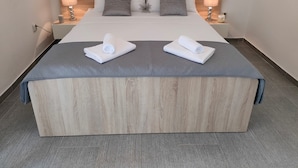 Un lit bien fait, avec deux serviettes blanches, une tête de lit en bois et deux lampes de chevet.